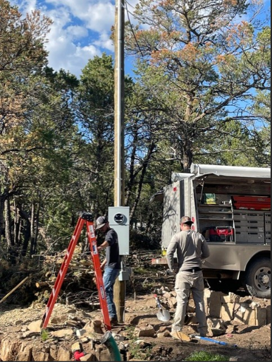 McFall Electric crew installing utility pole and panel outdoors